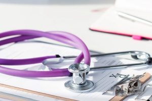 stethoscope lying on top of self insured plans papers