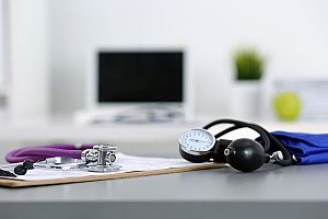 stethoscope and blood pressure monitor sitting on group health insurance paperwork in an office that plans to purchase it