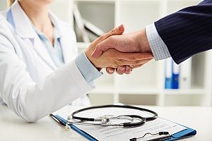 businessman shaking hands with a good doctor that he found through his group health insurance plan provided by his company