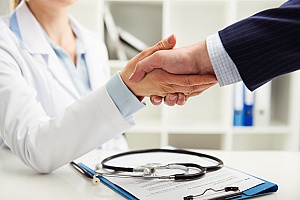 a medical doctor shaking hands with a benefits consultant who will discuss medical loss ration rebates with an insurance agent