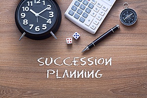 an alarm clock next to a pen and a calculator to represent how succession planning will help greatly benefit a business in the future