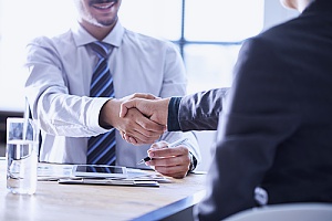 one of the business consultants at a business consulting firm shaking hands with a small business owner as they discuss the types of business insurance offered
