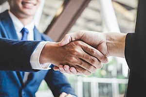 a current business owner shaking hands with a new business owner during business transfer