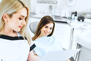 Woman talking to dentist about UCR dental in chair