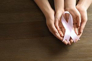 a pink cancer ribbon cupped in hands showing how cancer is a common type of long term disability