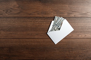 an envelope of money on a wood floor representing the salary replacement given in a long term disability policy