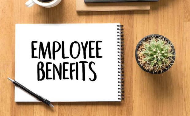 Word Employee benefits written on a notepad. Each year, employers are responsible for renewing employee benefits