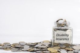 Coins with disability insurance labeled on a jar. Employee benefits package will foster a positive company culture