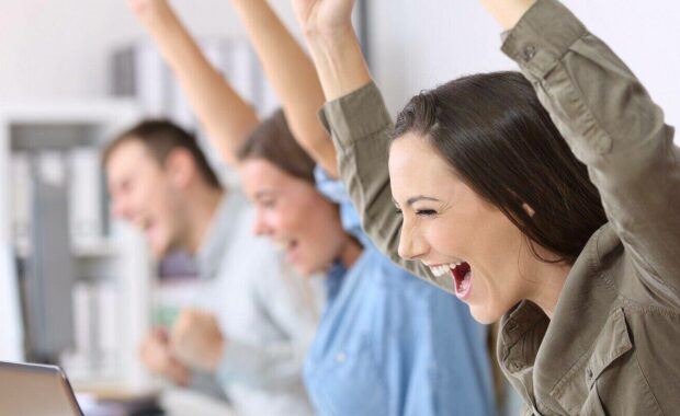 excited employees receiving good news on line in their laptops at office