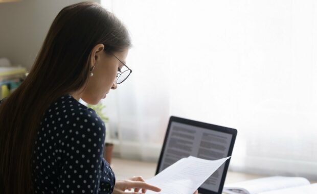 focused young woman in eyeglasses reading paper document
