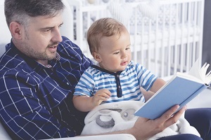 father with his baby on his laps reading a book