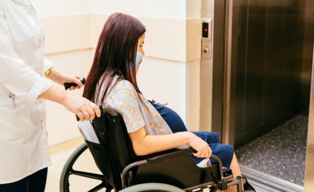female pregnant patient in the wheelchair through the hospital corridor