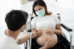 pregnant woman wear surgical mask to prevent disease and reduce the spread of various germs and sit on a wheelchair