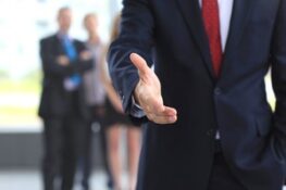 Benefits consultant raising his hand for hand shake while two colleagues are standing at some distance