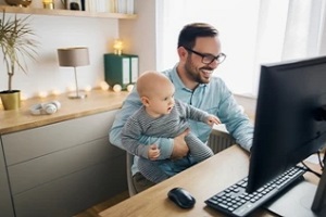 man working from home with baby in hands