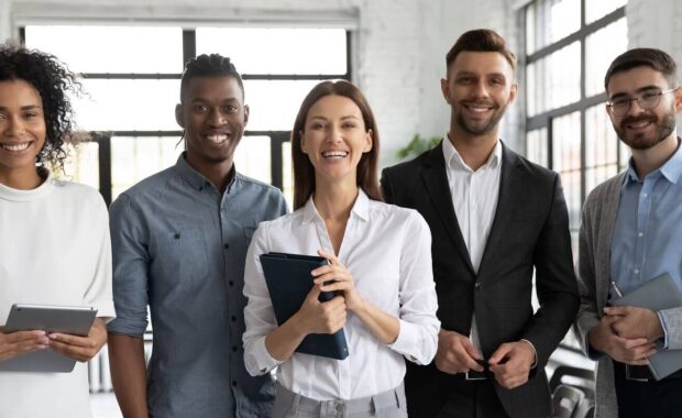 successful smiling diverse employees team standing in office