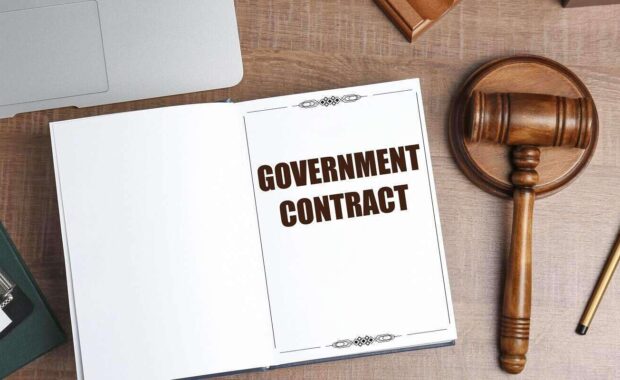 notebook with words government contract on wooden table
