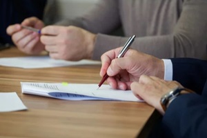 man signs a document during a business meeting or negotiations